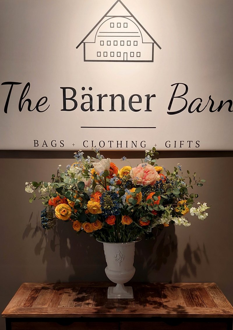 The Bärner Barn Logo an der Wand über einem üppigen Blumenstrauss